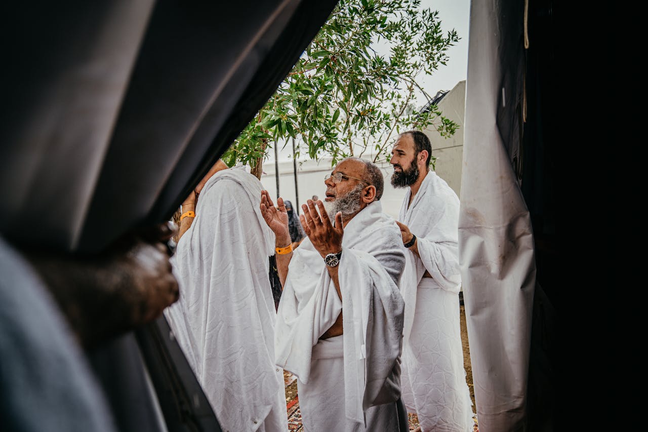 services-02 A group of men in white robes participate in a spiritual prayer outdoors, embracing cultural and religious traditions.